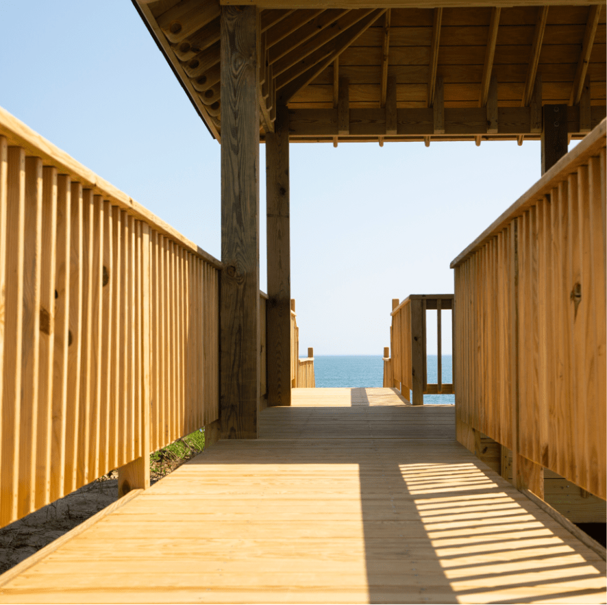 light wood deck walkway with gazebo leading to body of water